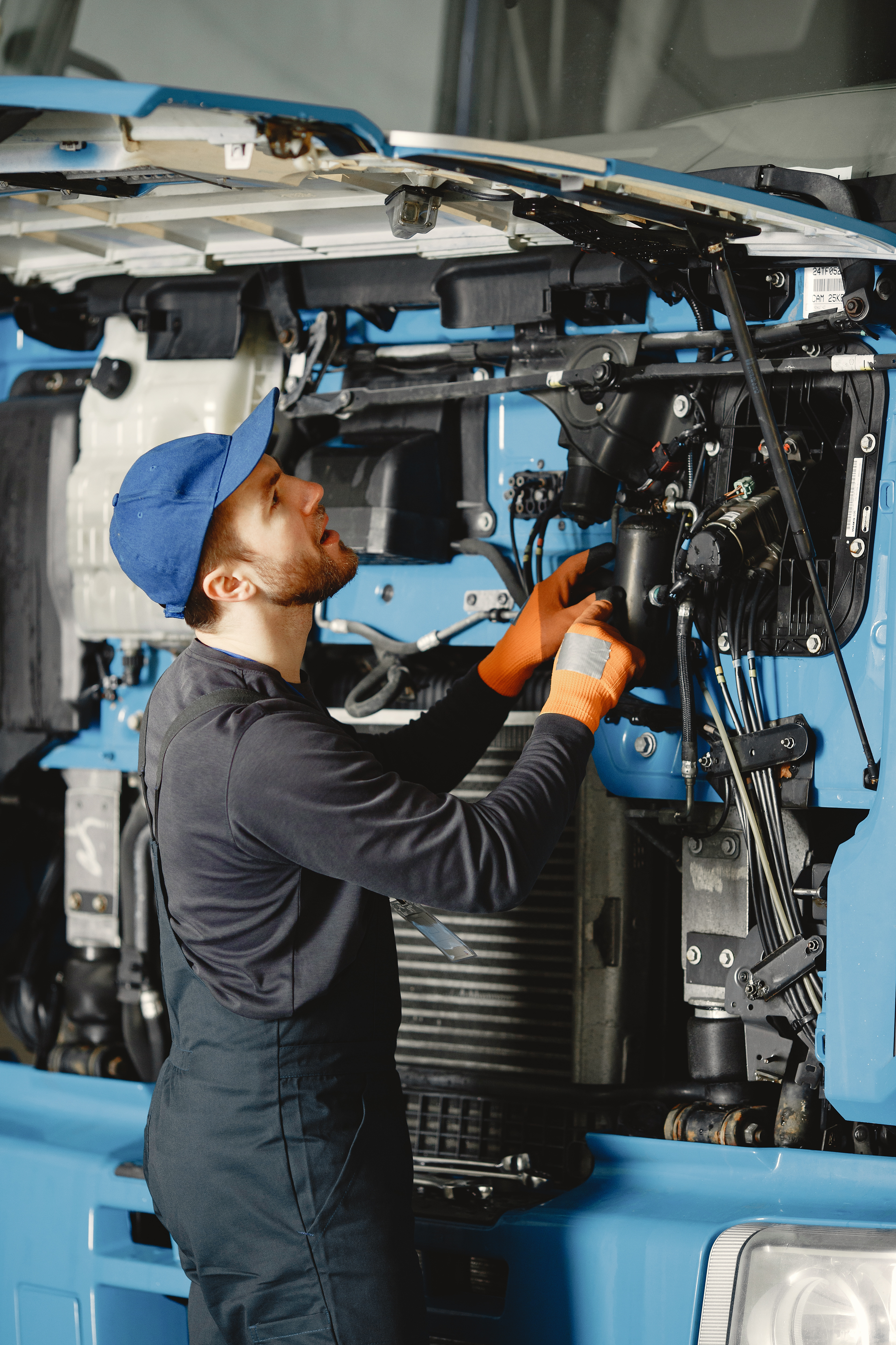 Worker checks quality of truck in garage in uniform